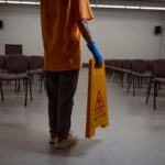 Mindful janitor putting a yellow warning sign on the wet floor