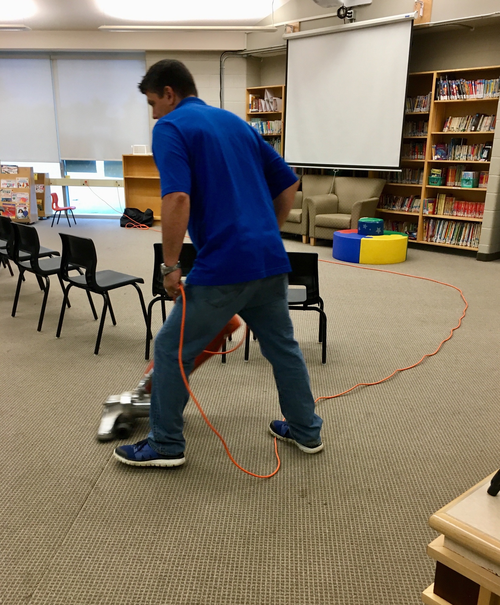 Professional cleaner working at office vacuuming floors